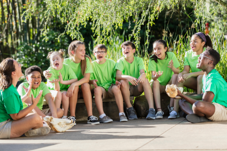 Kids sitting outside at summer camp wearing green shirts