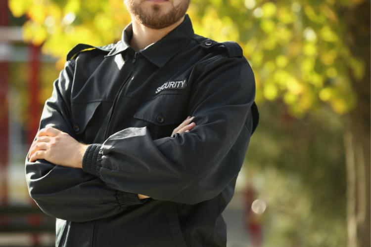 Uniformed security guard standing outside near trees