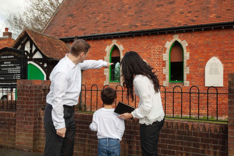 A family with a young child standing near a church 