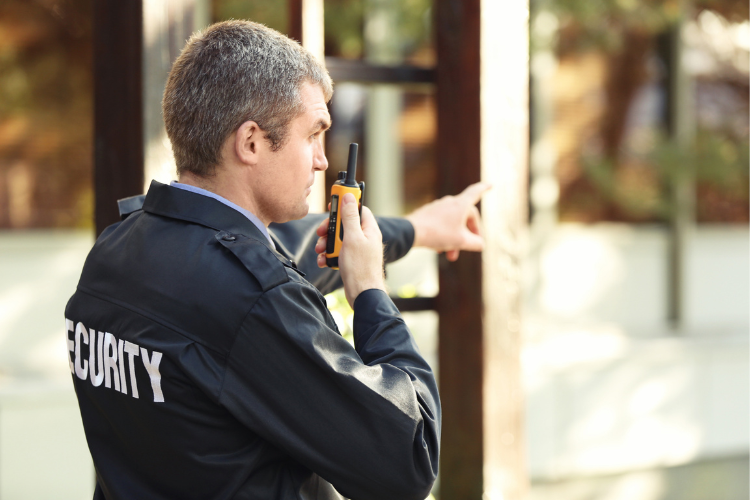 Security guard outside pointing while talking on a radio